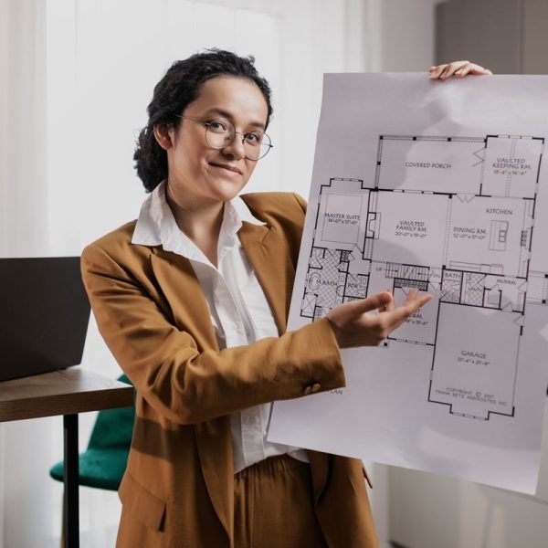 Female architect presenting a detailed floor plan indoors, showcasing design expertise.